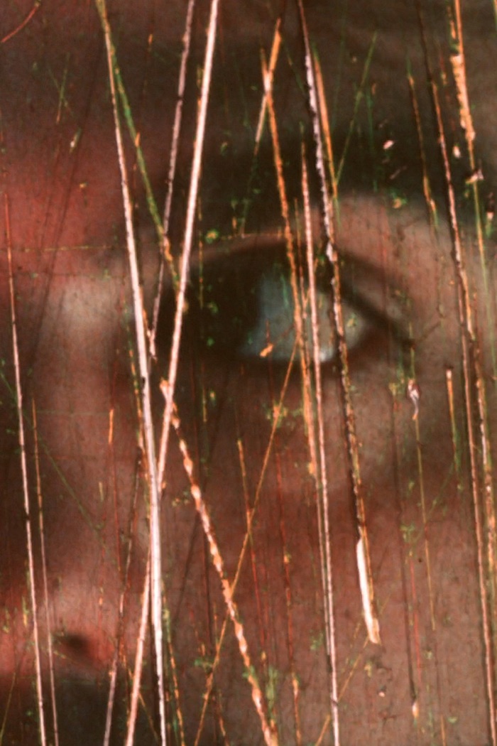 Poster for Eroticristo: a close-up of an eye seen through a scratched, color-stained 16mm film frame.